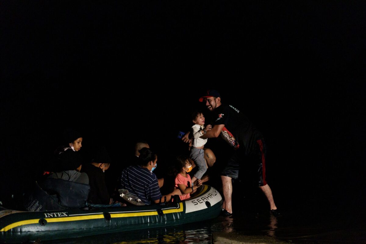 A human smuggler carries toddler on July 6, 2021 [PAUL RATJE/AFP via Getty Images]