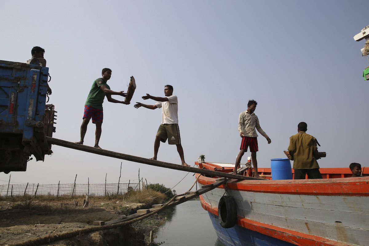 Rohingya laborers unload firewood from a boat to truck as they work at a brick production workplace in a village on December 23, 2021, in Sittwe, Rakhine State, Myanmar [Aung Naing Soe - Anadolu Agency]