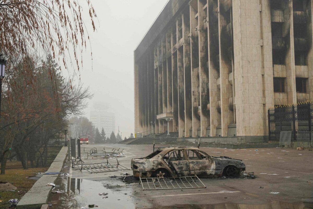 TOPSHOT - This general view shows a vehicle in front of a burnt-out administrative building in central Almaty on January 7, 2022, after violence that erupted following protests over hikes in fuel prices. - Kazakhstan's president has rejected calls for talks with protesters after days of unprecedented unrest, vowing to destroy "armed bandits" and authorising his forces to shoot to kill without warning. He said earlier that order had mostly been restored across the country, after protests this week over fuel prices escalated into widespread violence, especially in main city Almaty. (Photo by Alexandr BOGDANOV / AFP) (Photo by ALEXANDR BOGDANOV/AFP via Getty Images)