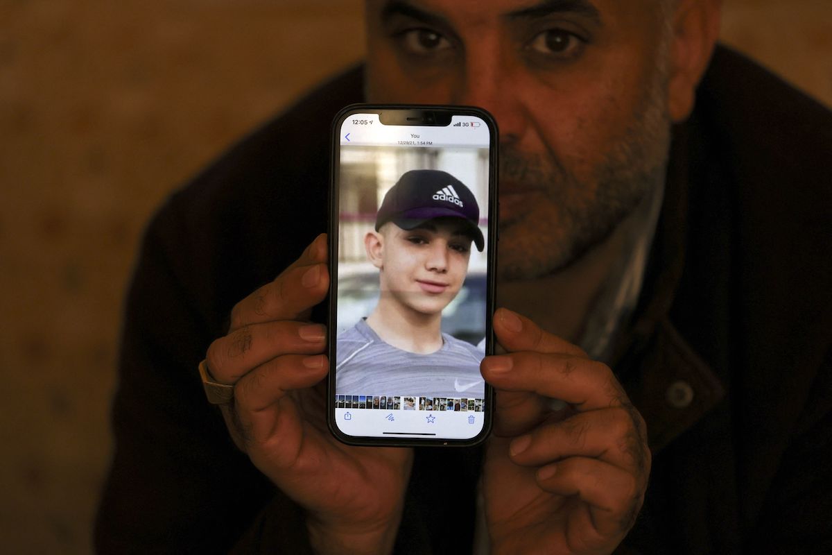 Moammar Nakhleh, the father of 17 year-old Palestinian prisoner Amal, shows a photograph of his son on his telephone, in Jalazun refugee camp, near the occupied West Bank city of Ramallah, on 8 January 2022. [ABBAS MOMANI/AFP via Getty Images]