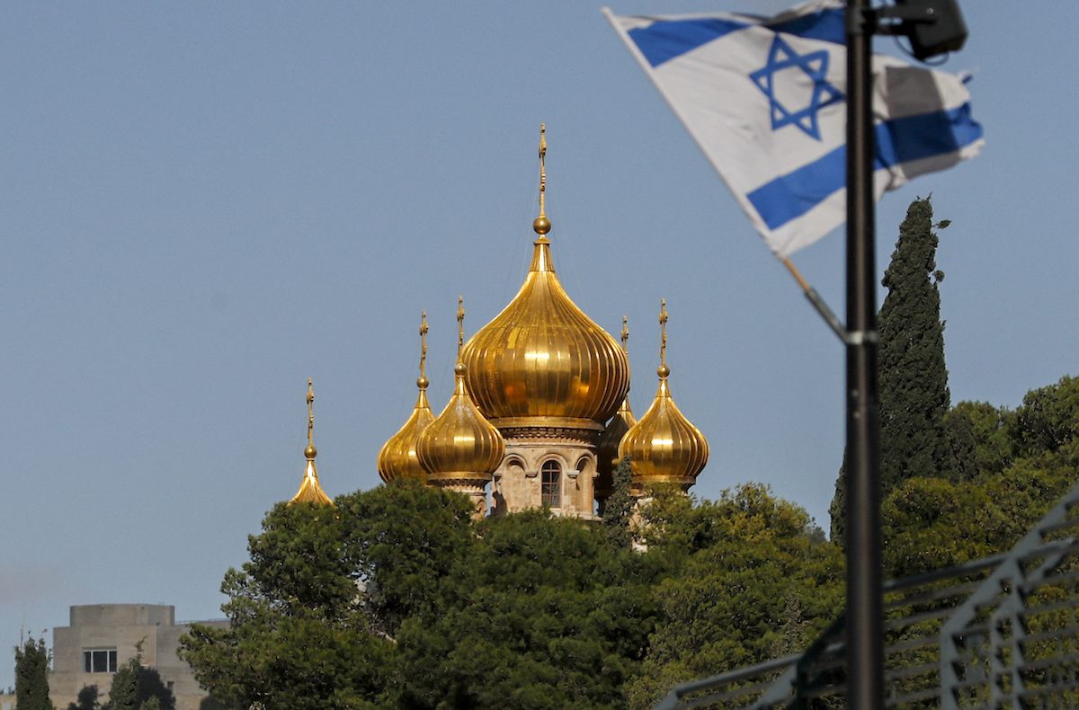 This picture taken on December 20, 2021 shows a view of an Israeli flag flying near the Russian Orthodox Church of Mary Magdalene atop the Mount of Olives in Jerusalem. [AHMAD GHARABLI/AFP via Getty Images]