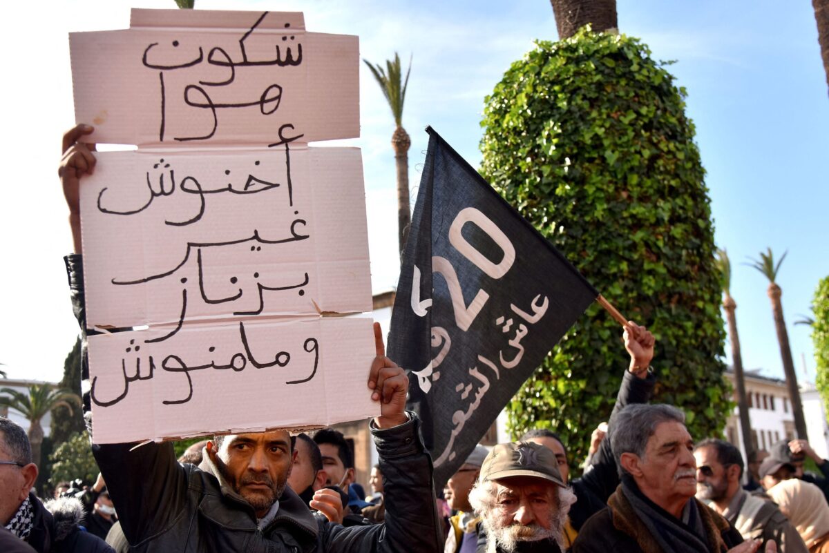 A Moroccan man raises a placard as he takes part in a protest against rising prices, in front of the parliament in the capital Rabat, on February 20, 2022. (Photo by AFP) (Photo by STR/AFP via Getty Images)