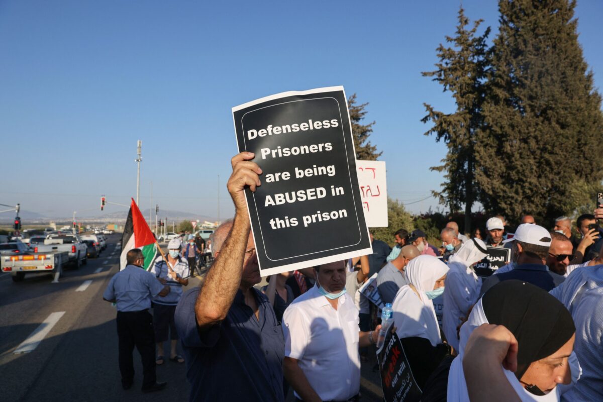 Arab Israelis lift Palestinian flags and placards during a protest outside the Megiddo prison in northern Israel on August 22, 2021, to demand the release of prisoners from their community jailed following clashes with Jewish Israelis in May in Lod and other cities [AHMAD GHARABLI/AFP via Getty Images]