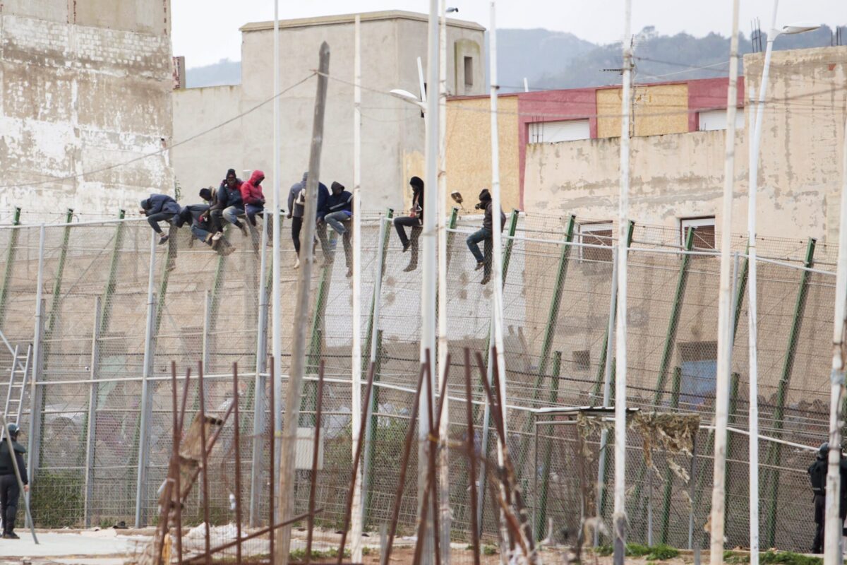 Immigrants sit atop a border fence after attempting to cross from Morocco to the Spanish enclave of Melilla on February 10, 2015 [ANGELA RIOS/AFP via Getty Images]