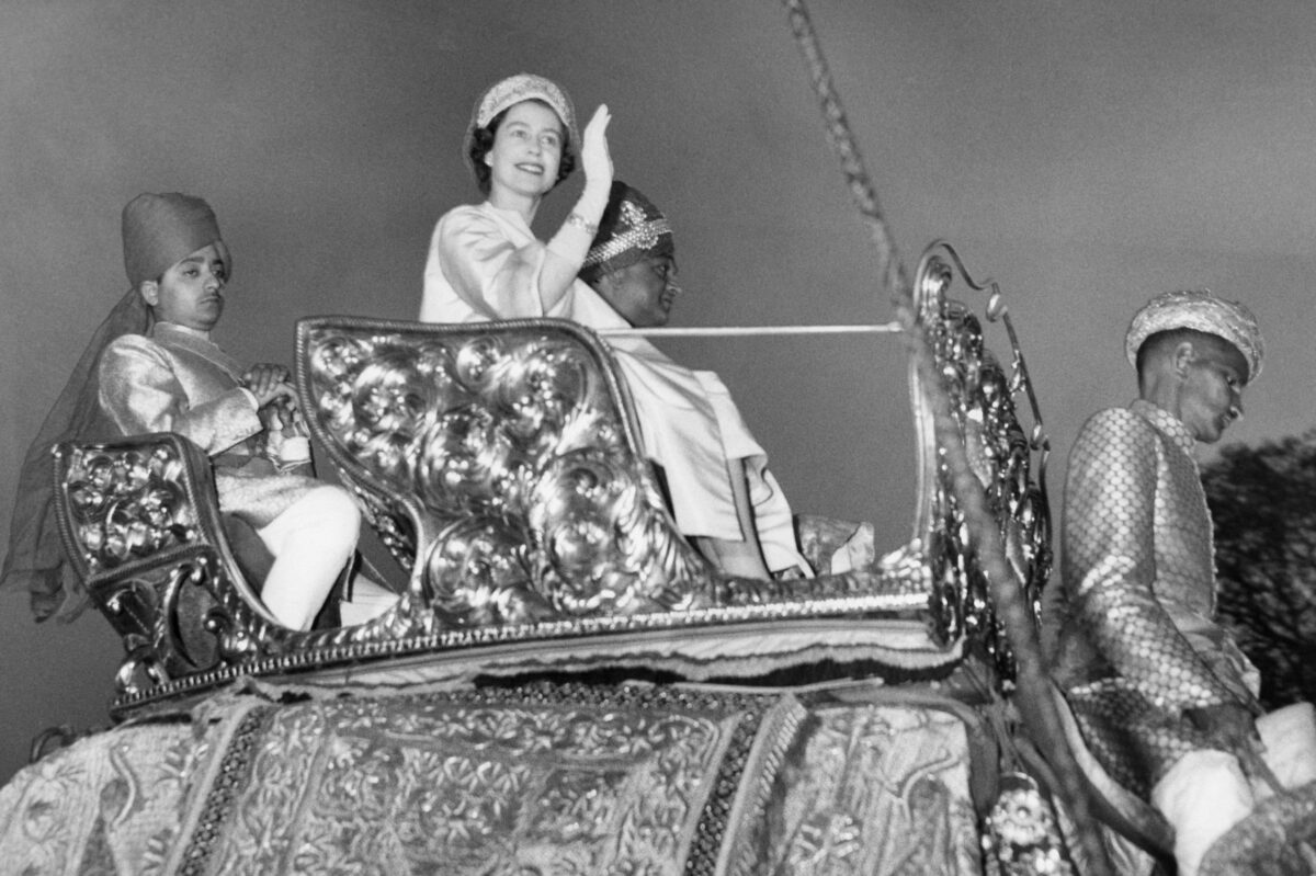 Britain's Queen Elizabeth II waves to the crowd as she rides an elephant next to Maharaja of Jaipur Man Singh II at the City Palace in Jaipur on January 24, 1961. (Photo by - / CENTRAL PRESS / AFP) (Photo by -/CENTRAL PRESS/AFP via Getty Images)