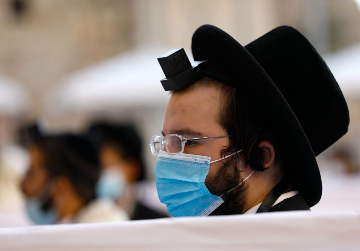An Ultra-Orthodox Jewish man wearing a facemask and a tefillin prays at the Western Wall in the Old City of Jerusalem on October 18, 2020, amid the novel coronavirus pandemic crisis. - Israel began to ease its month-long coronavirus nationwide lockdown, allowing citizens to venture further than 1km (0.6 miles) away from their home with preschools, daycare centres and places of worship reopening to all, under some restrictions. (Photo by Emmanuel DUNAND / AFP) (Photo by EMMANUEL DUNAND/AFP via Getty Images)