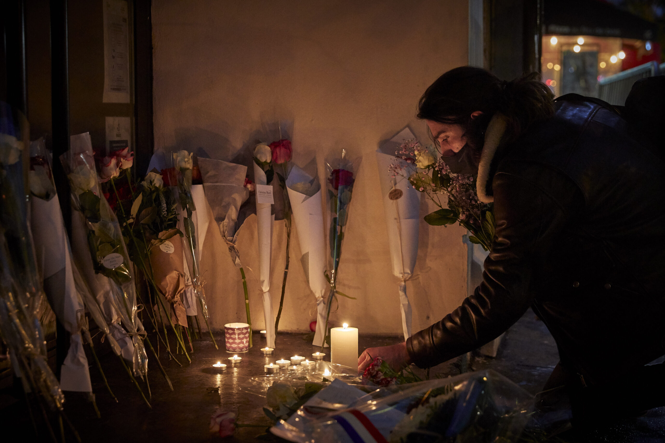 A Parisian lights a candle outside the Bataclan concert hall in memory of the victims who were killed during the 13th November 2015 Paris terror [Kiran Ridley/Getty Images]