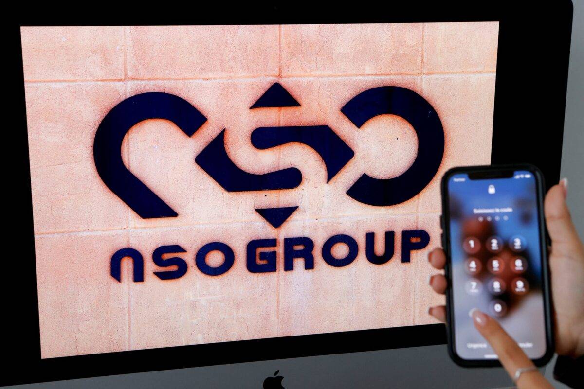 A photographic illustration shows a mobile phone near the NSO Group company logo in the Israeli city of Netanya [JACK GUEZ/AFP via Getty Images]