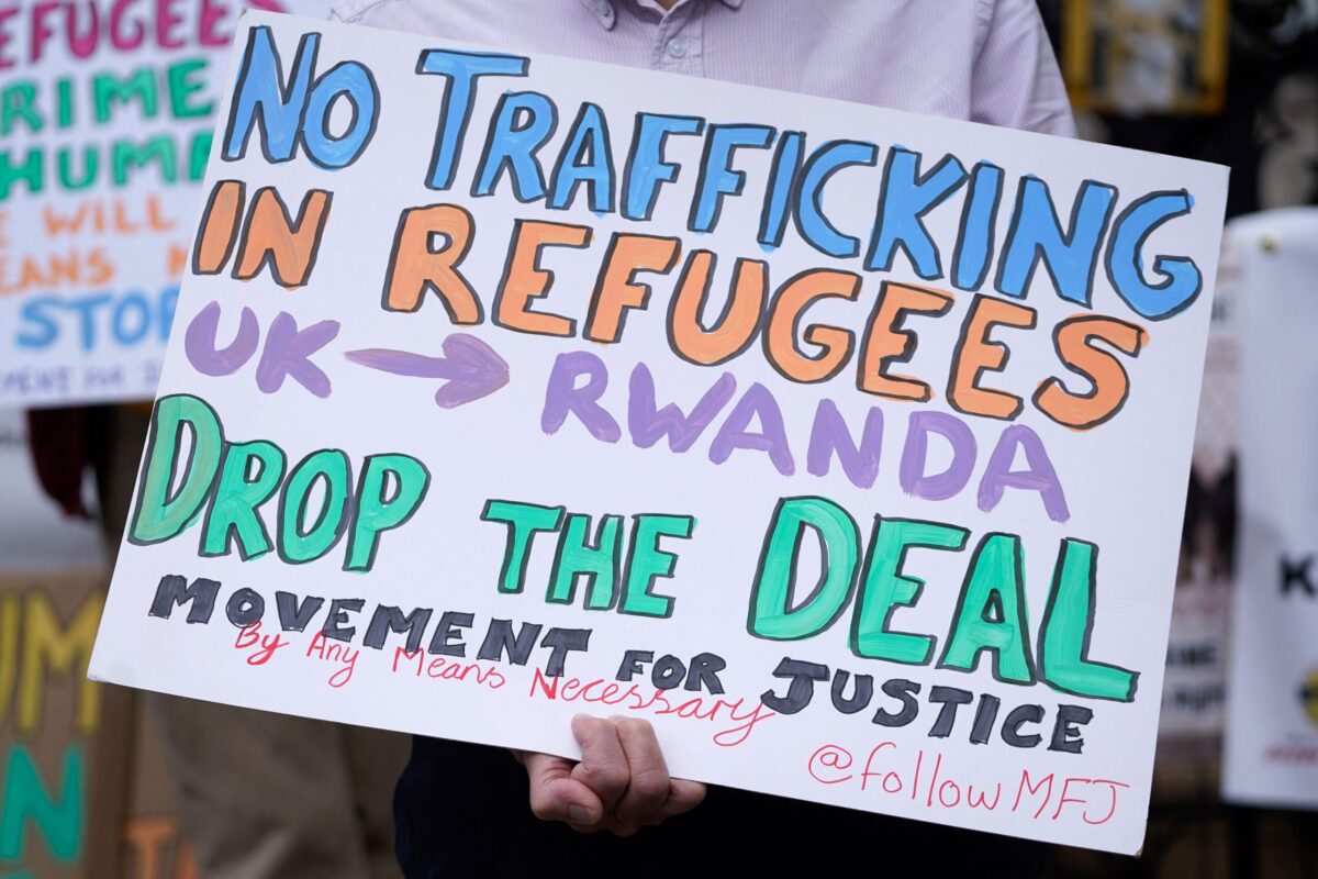 Demonstrators hold placards as they protest against Britain's plan to deport asylum seekers to Rwanda, outside the High Court in London on June 13, 2022 [NIKLAS HALLE'N/AFP via Getty Images]