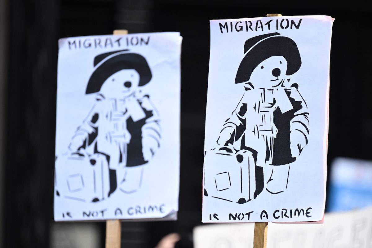Placards depicting Paddington Bear and the words "Migration is not a crime" are displayed as people protest against the UK deportation flights to Rwanda outside the Home Office on June 14, 2022 in London, England. [Leon Neal/Getty Images]