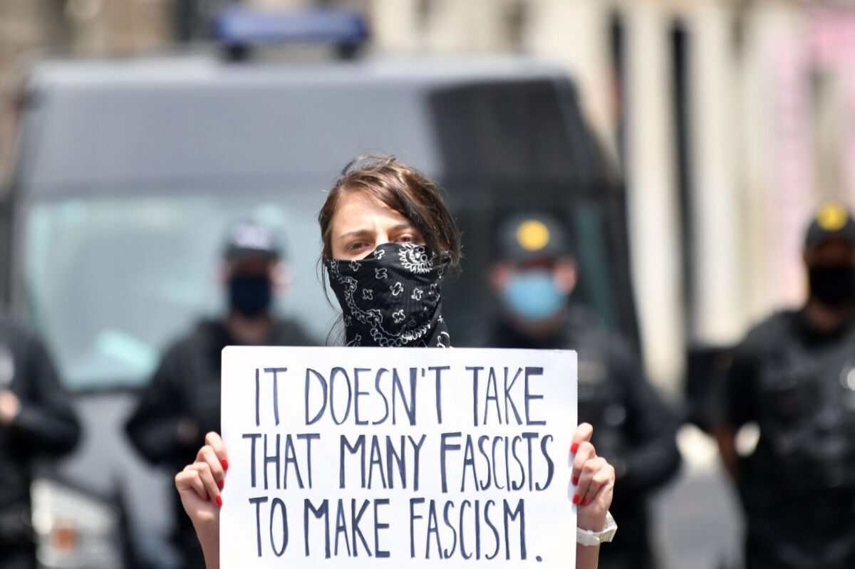 A woman holds a sign as people, some wearing protective face masks against the novel coronavirus, COVID-19, gather in Sarajevo's city center to protest against a religious mass taking place in memory of Croatia's pro-Nazi collaborators and civilians killed by communist partisans after World War II on May 16, 2020. - Sarajevans protested against the religious mass, held on May 16, in the city cathedral for Croatia's pro-Nazi collaborators and civilians killed by communist partisans after World War II. The mass provoked outrage from most political parties and non-governmental organisations as well as the Serbian Orthodox Church and Jewish leaders. (Photo by ELVIS BARUKCIC / AFP) (Photo by ELVIS BARUKCIC/AFP via Getty Images)