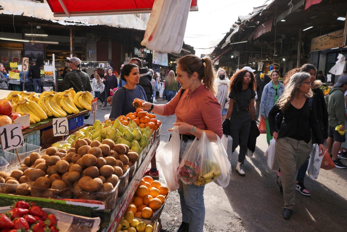 A woman shops at a street market in the center of Israel's Mediterranean coastal city of Tel Aviv on December 1, 2021 [MENAHEM KAHANA/AFP via Getty Images]