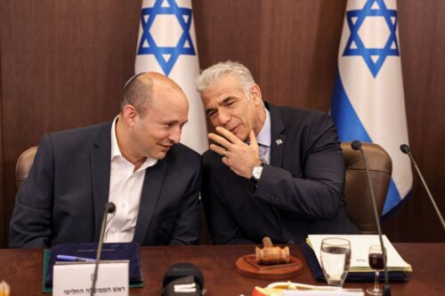 (R to L) Israel's caretaker Prime Minister Yair Lapid speaks with former prime minister Naftali Bennett during the weekly cabinet meeting in Jerusalem, on September 18, 2022 [Photo by RONALDO SCHEMIDT/POOL/AFP via Getty Images]
