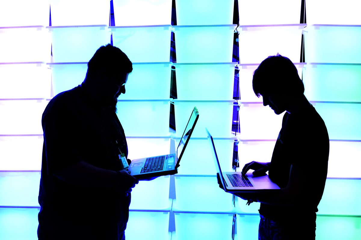 Participant hold their laptops in front of an illuminated wall at the annual Chaos Computer Club (CCC) computer hackers' congress, called 29C3, in Hamburg, Germany, on December 28, 2012 [Photo by Patrick Lux/Getty Images]