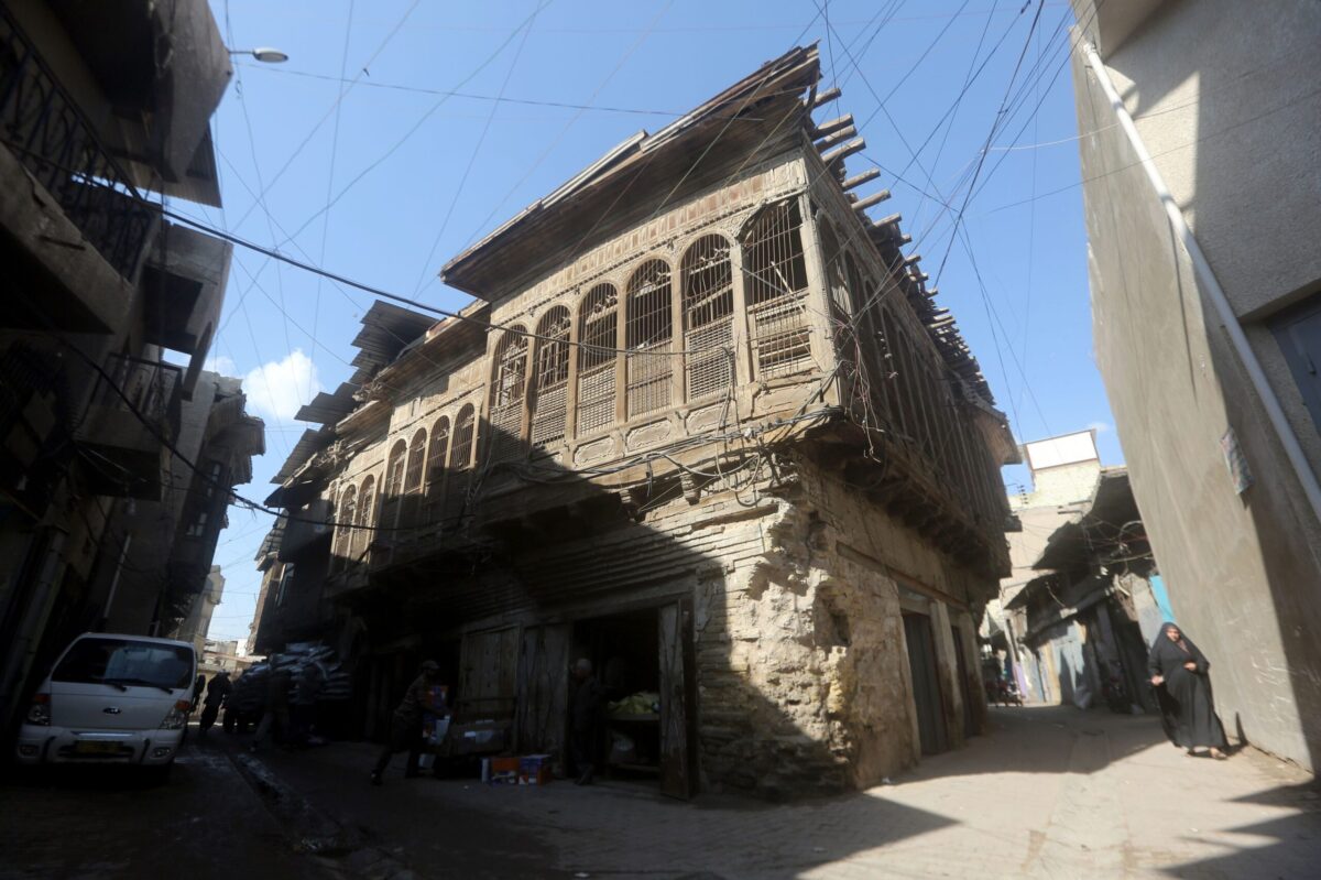 An Iraqi woman walks next to a historic house made from mud bricks and wood in al-Sadriya neighbourhood in Baghdad, on February 24, 2016 [AHMAD AL-RUBAYE/AFP via Getty Images]