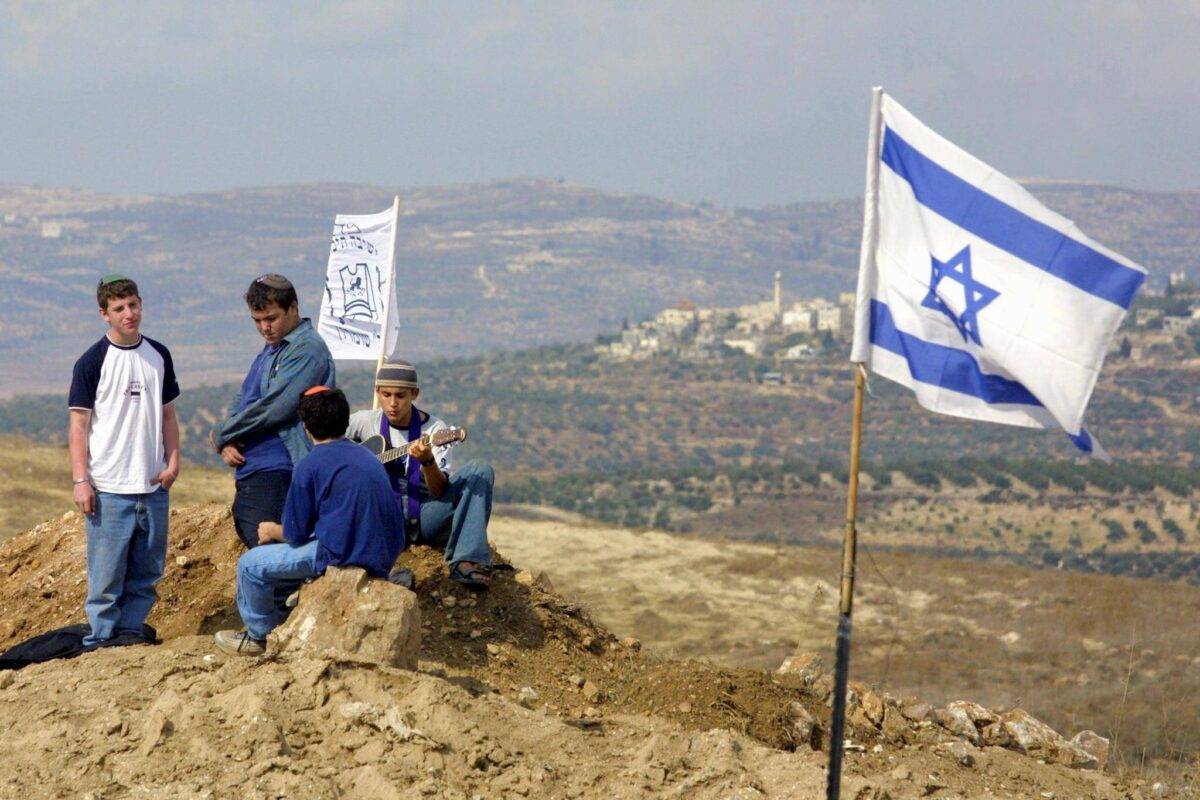 A group of the settlers play music outside the rogue settlement of Havat Gilad, near Nablus, in the West Bank 16 October 2002 [GALI TIBBON/AFP via Getty Images]