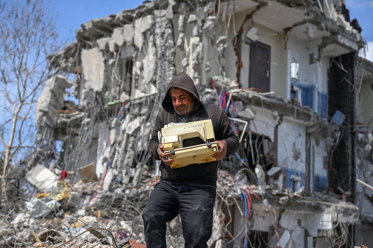 A man carries sewing machine near debris as demolishing and removal works continue after 7.7 and 7.6 magnitude earthquakes hit multiple provinces of Turkiye [Özkan Bilgin - Anadolu Agency]