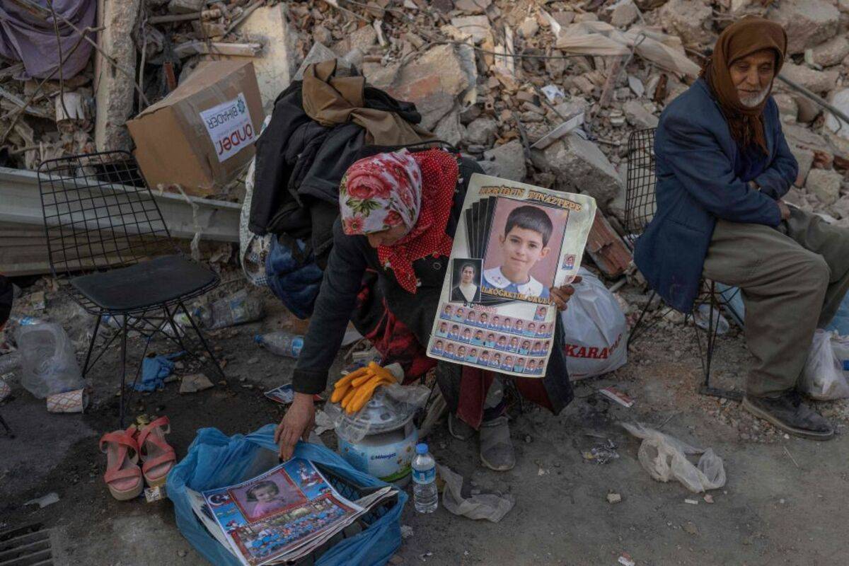 A woman holds her grandchildren pictures who is missing in Hatay after a 7,8 magnitude earthquake struck the border region of Turkey and Syria earlier in the week. [BULENT KILIC/AFP via Getty Images]