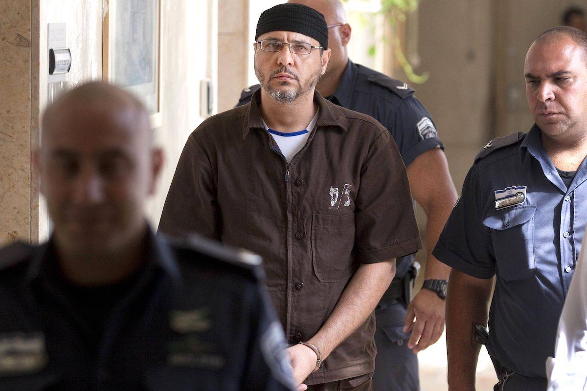 Palestinian Abdullah Barghouti, a leading commander for the Ezzedine al-Qassam Brigades, the armed wing of Hamas in the West Bank, is escorted by Israeli police into the Magistrate's Court for a hearing in Jerusalem on June 20, 2012. [MENAHEM KAHANA/AFP via Getty Images]