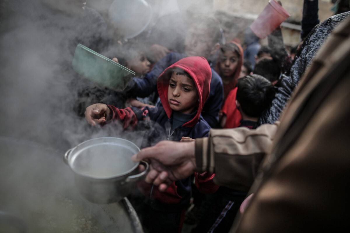 Children wait for taking the soup distributed for people in need by a charity in Gaza on March 24, 2023 [Ali Jadallah/Anadolu Agency]