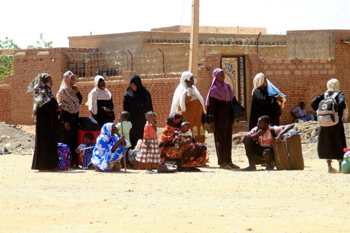 People fleeing street battles between the forces of two rival Sudanese generals, wait with their belongings along a road in the southern part of Khartoum, on April 21, 2023 [AFP via Getty Images]