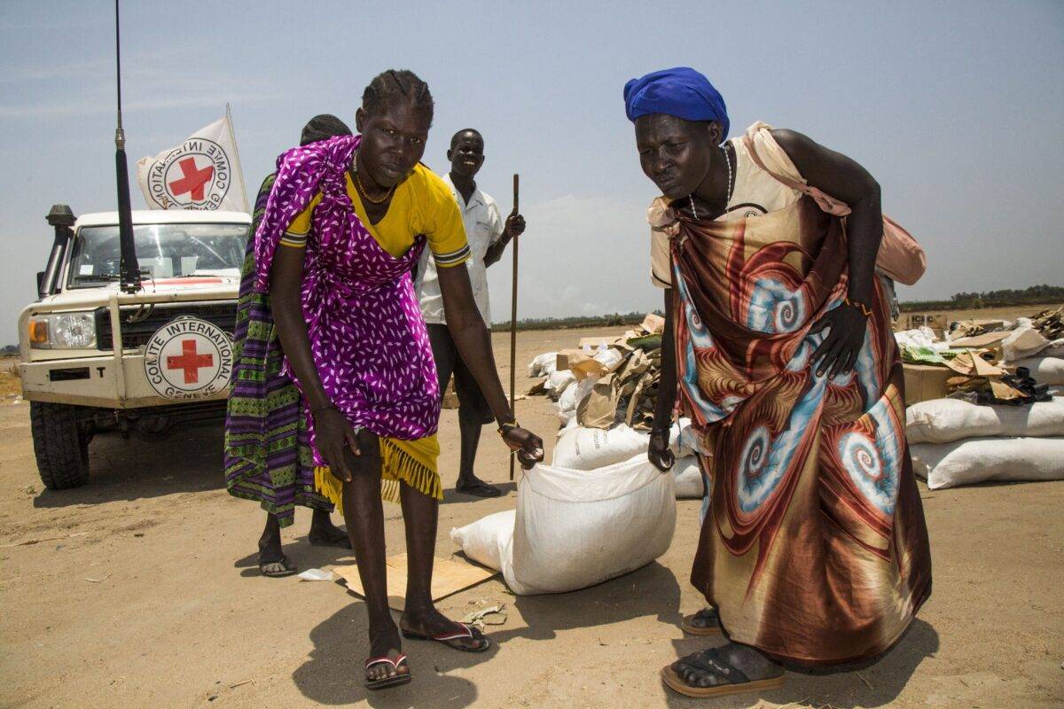 Women carry a sack of seeds distributed by the International Committee of the Red Cross (ICRC) in the opposition controlled town of Thonyor, in Sudan on April 11, 2017 [ALBERT GONZALEZ FARRAN/AFP via Getty Images]