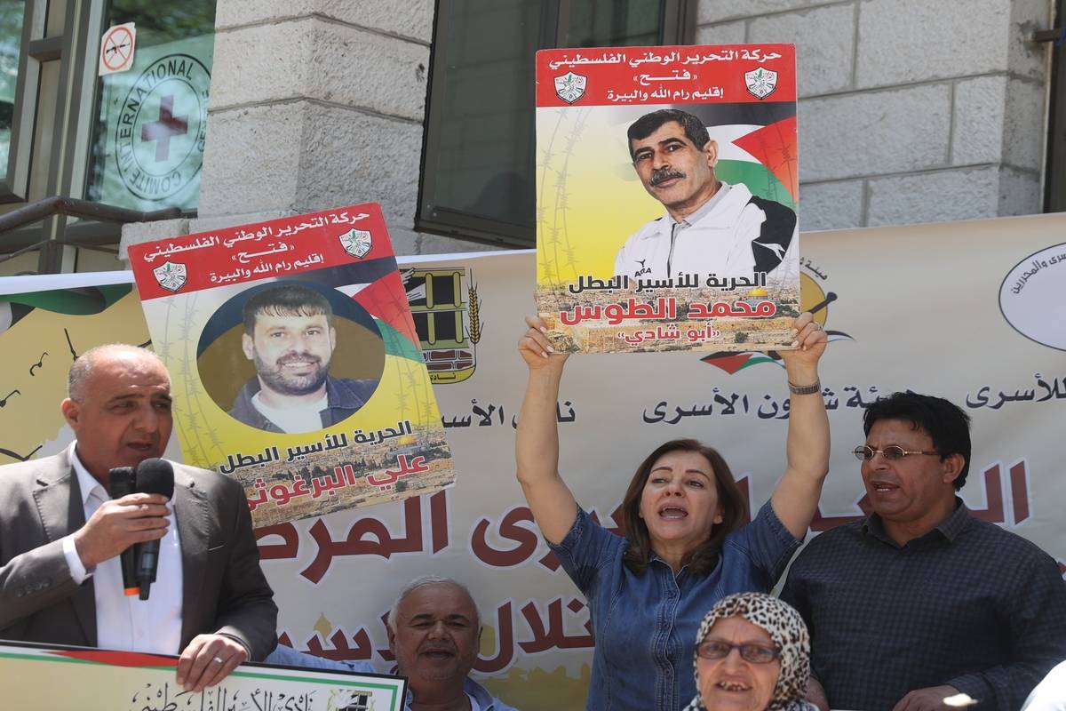 People, holding photos of prisoners, gather for a solidarity demonstration for Palestinian prisoners held in Israeli jails in front of Red Cross building in Ramallah, West Bank on May 30, 2023. [Issam Rimawi - Anadolu Agency]