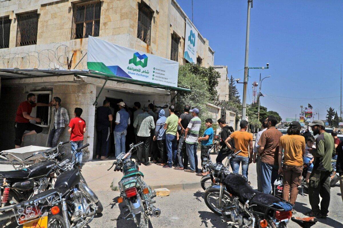 Syrians queue outside a currency exchange shop in Syria's northwestern city of Idlib, on June 15, 2020 [AAREF WATAD/AFP via Getty Images]