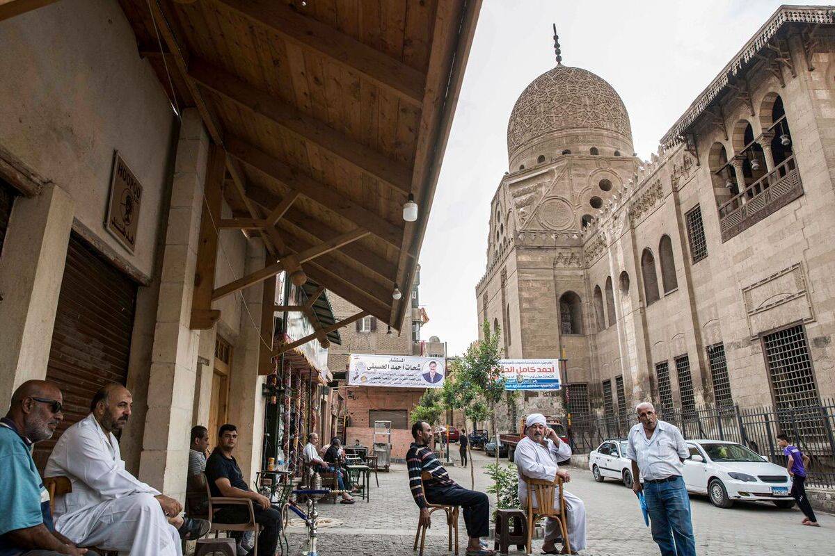 Men sit at a cafe by the 15th century Sultan Qaitbay mosque complex in the "Desert of the Mamluks" (City of the Dead) area of Egypt's capital Cairo [KHALED DESOUKI/AFP via Getty Images]