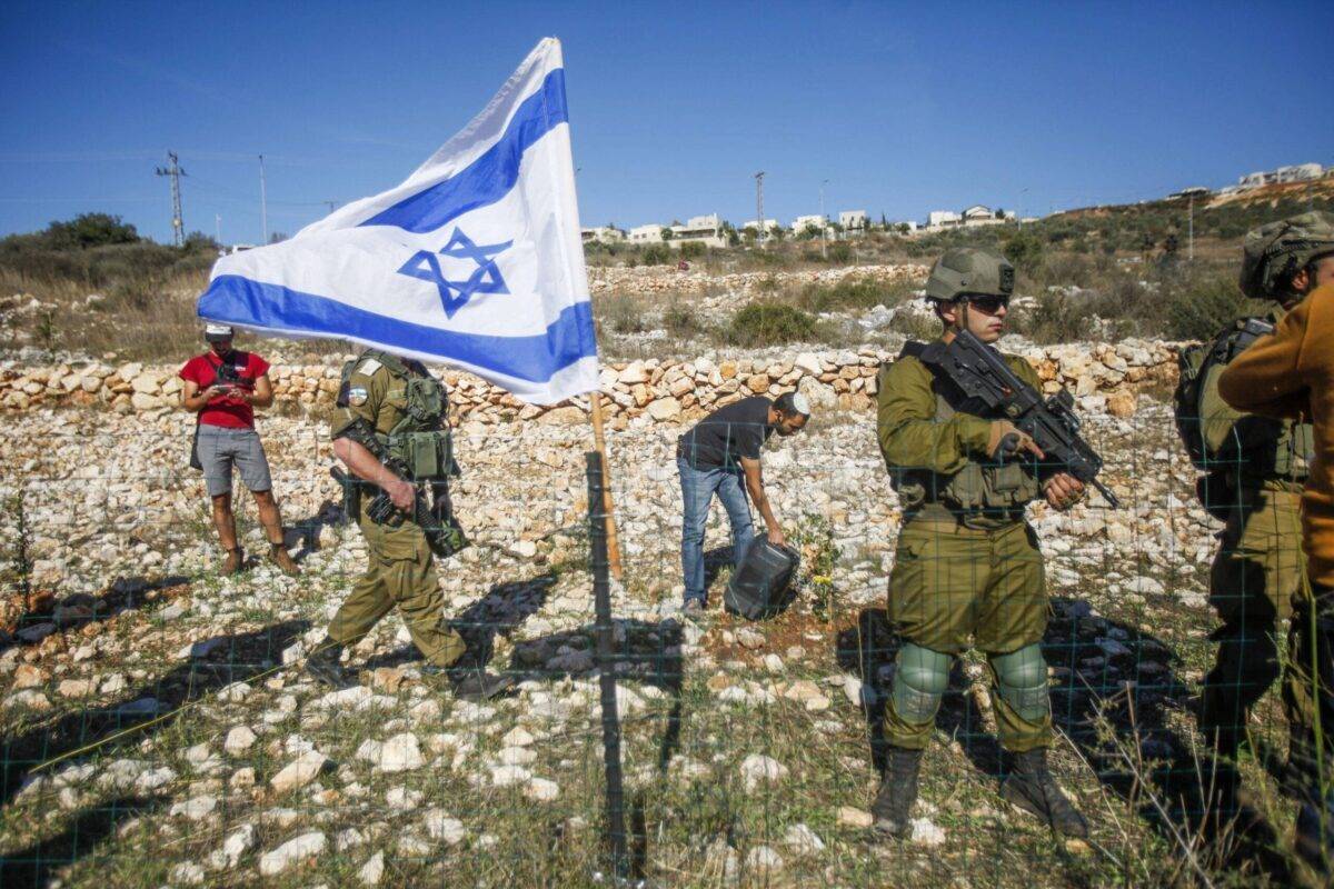 Israeli soldiers guard Jewish settlers as they seize the lands of Palestinian farmers in the village of Burqin, west of Salfit, in the occupied West Bank [Nasser Ishtayeh/SOPA Images/LightRocket via Getty Images]