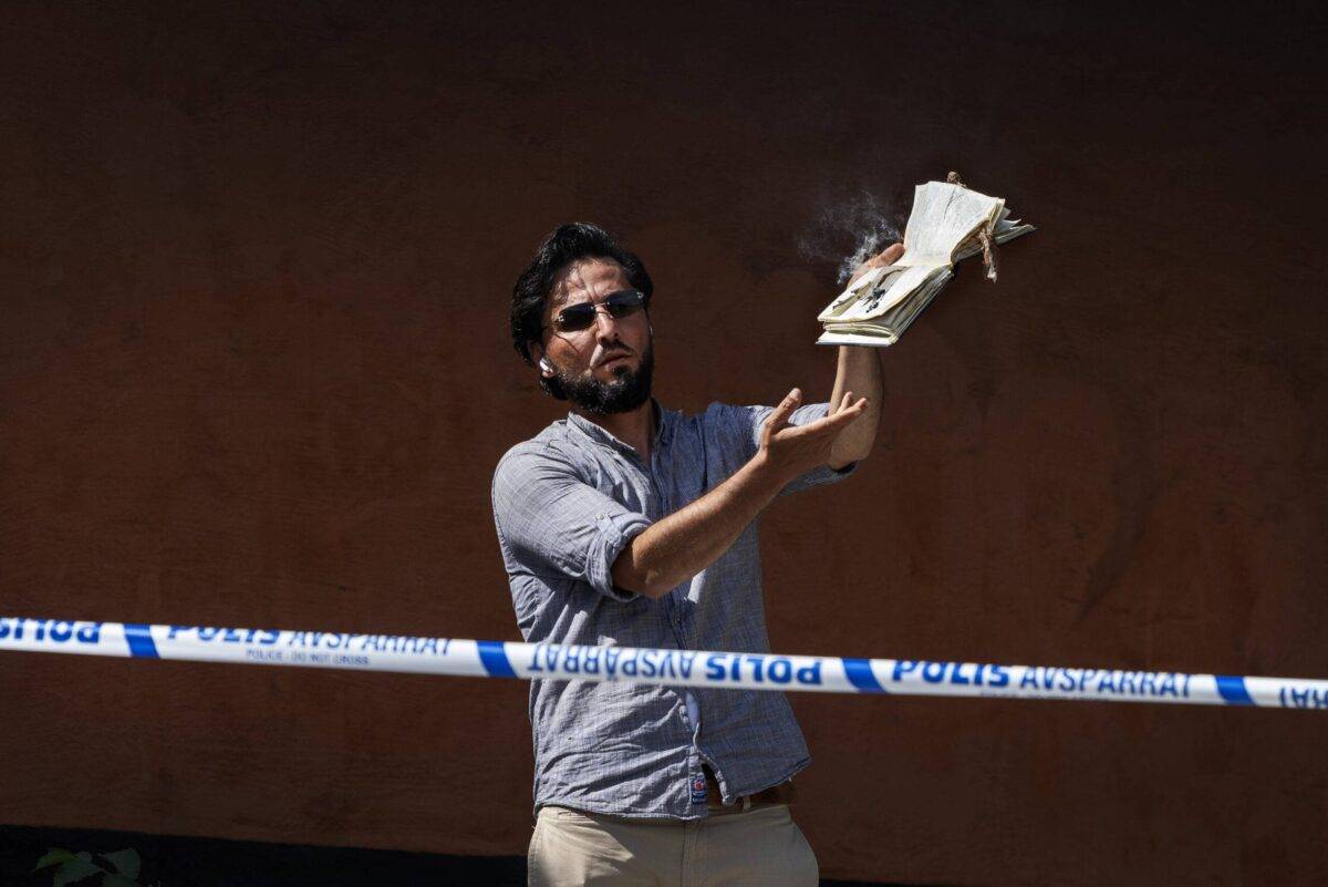 A man burns a Quran and covers it with bacon at the Stockholm mosque on June 28, 2023 in Stockholm, Sweden [Nils Petter Nilsson/Getty Images]