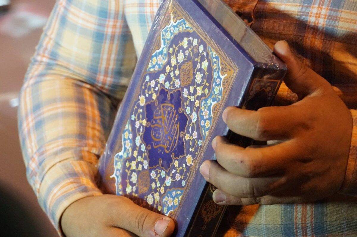 People present the Holy Quran to the drivers of a passing car on the main street in Tisin district of Kirkuk, Iraq on July 05, 2023. [Ali Makram Ghareeb - Anadolu Agency]