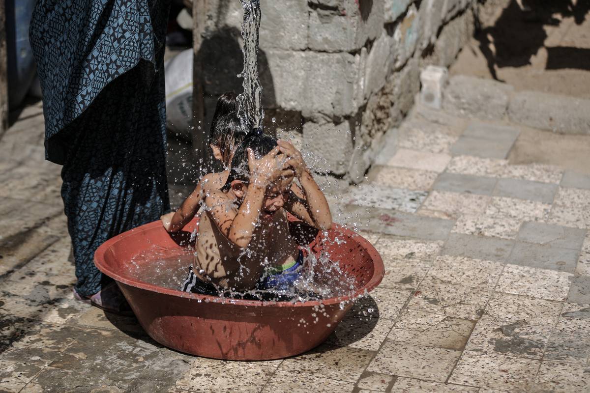 Children try to cool off with cold water as the blistering heat scorches Gaza City, Gaza on July 19, 2023 [Ali Jadallah - Anadolu Agency]