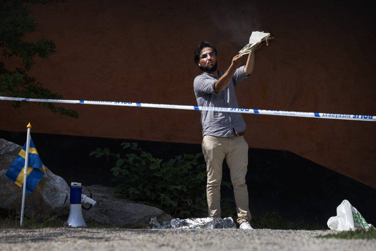 A man burns a koran and covers it with bacon at the Stockholm mosque on June 28, 2023 in Stockholm, Sweden [Nils Petter Nilsson/Getty Images]