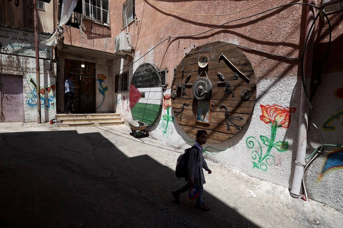 A girl walks with a school bag despite the damaged parts of Palestinian refugee camp Nur Shams after a raid by Israeli forces in Tulkarem, West Bank on August 02, 2023. [ Issam Rimawi - Anadolu Agency]
