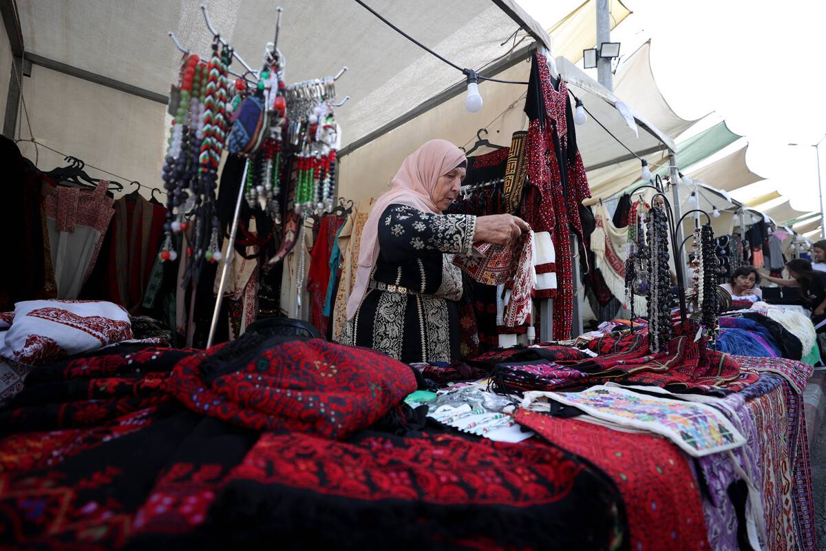 A Palestinian vendor shows the product to a customer at Al Harajah bazaar in Ramallah, West Bank on August 18, 2023. "Al Harajah" market was established by the municipality of Ramallah to preserve Palestinian culture. [ Issam Rimawi - Anadolu Agency ]