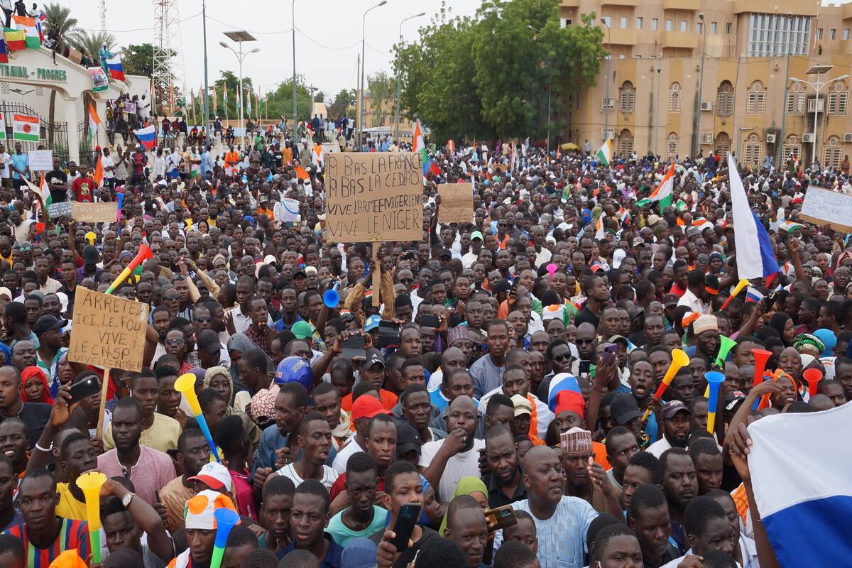 Coup supporters wave flags during the protest against a possible military intervention by the Economic Community of West African States (ECOWAS) bloc and sanctions in Niamey, Niger on August 20, 2023 [Balima Boureima/Anadolu Agency]