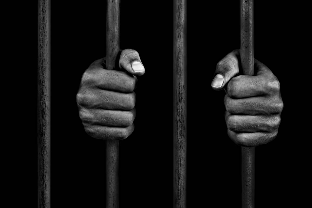 Hands of a prisoner on prison bars Hands of a prisoner on prison bars [ Photo via Getty Images]