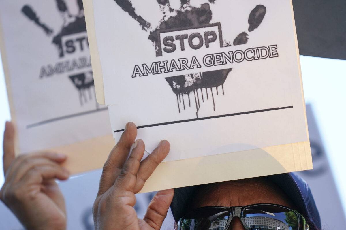 People hold up signs at a demonstration to bring awareness to the mass ethnic cleansing of ethnic Amharas in the Gimby Zone in Western Wollege, Oromia Region in Ethiopia on June 30, 2022 in Washington, DC [J. Countess/Getty Images]