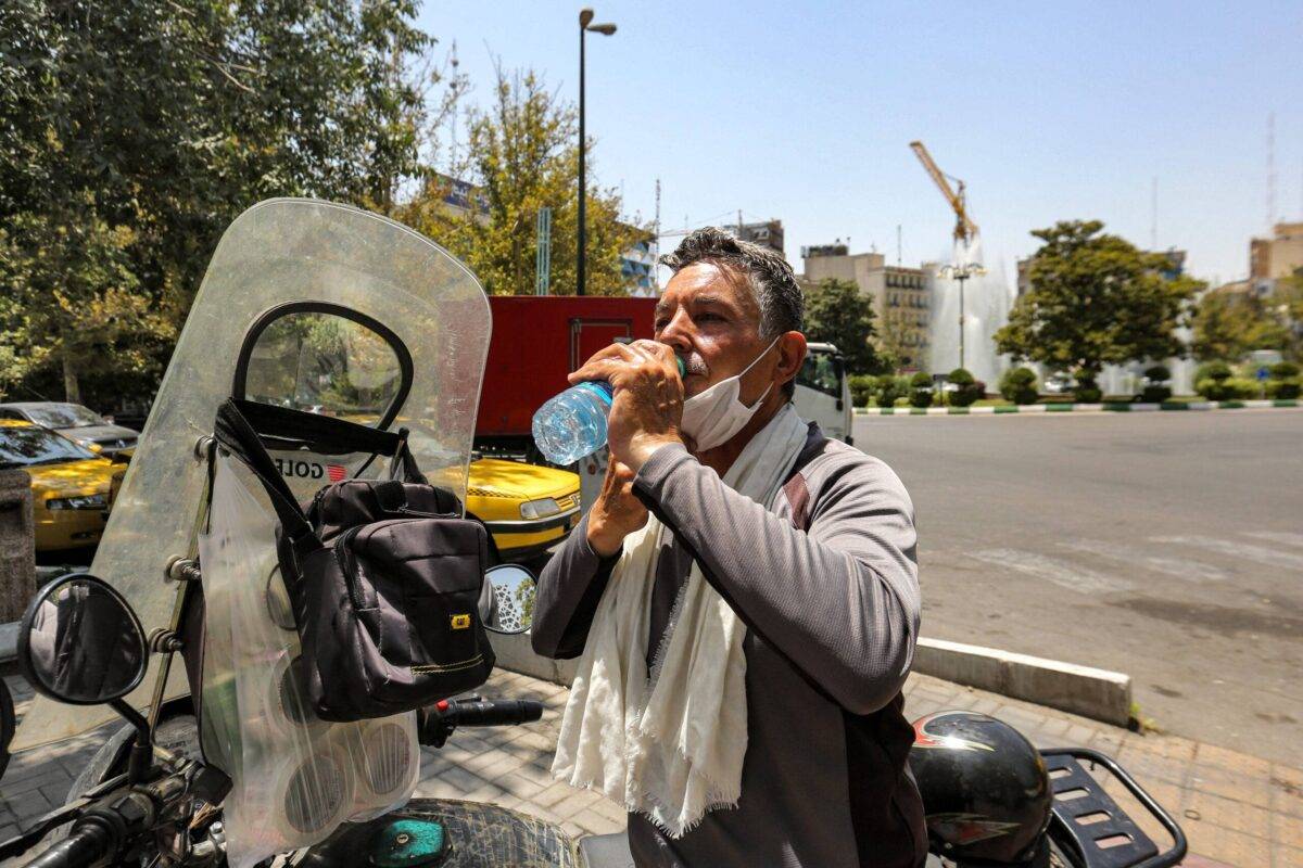 A motorcyclist has a drink from a bottle to cool off during a heat wave in Tehran on July 11, 2023 [ATTA KENARE/AFP via Getty Images]