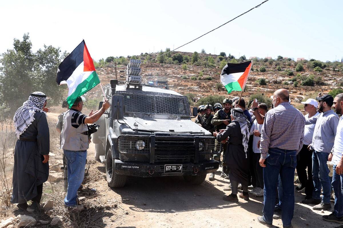 Palestinians stand in front of a military vehicle of Israeli forces as they demonstrate against construction of Jewish settlements in village of Qaryut of Nablus, West Bank on September 15, 2023 [Issam Rimawi - Anadolu Agency]