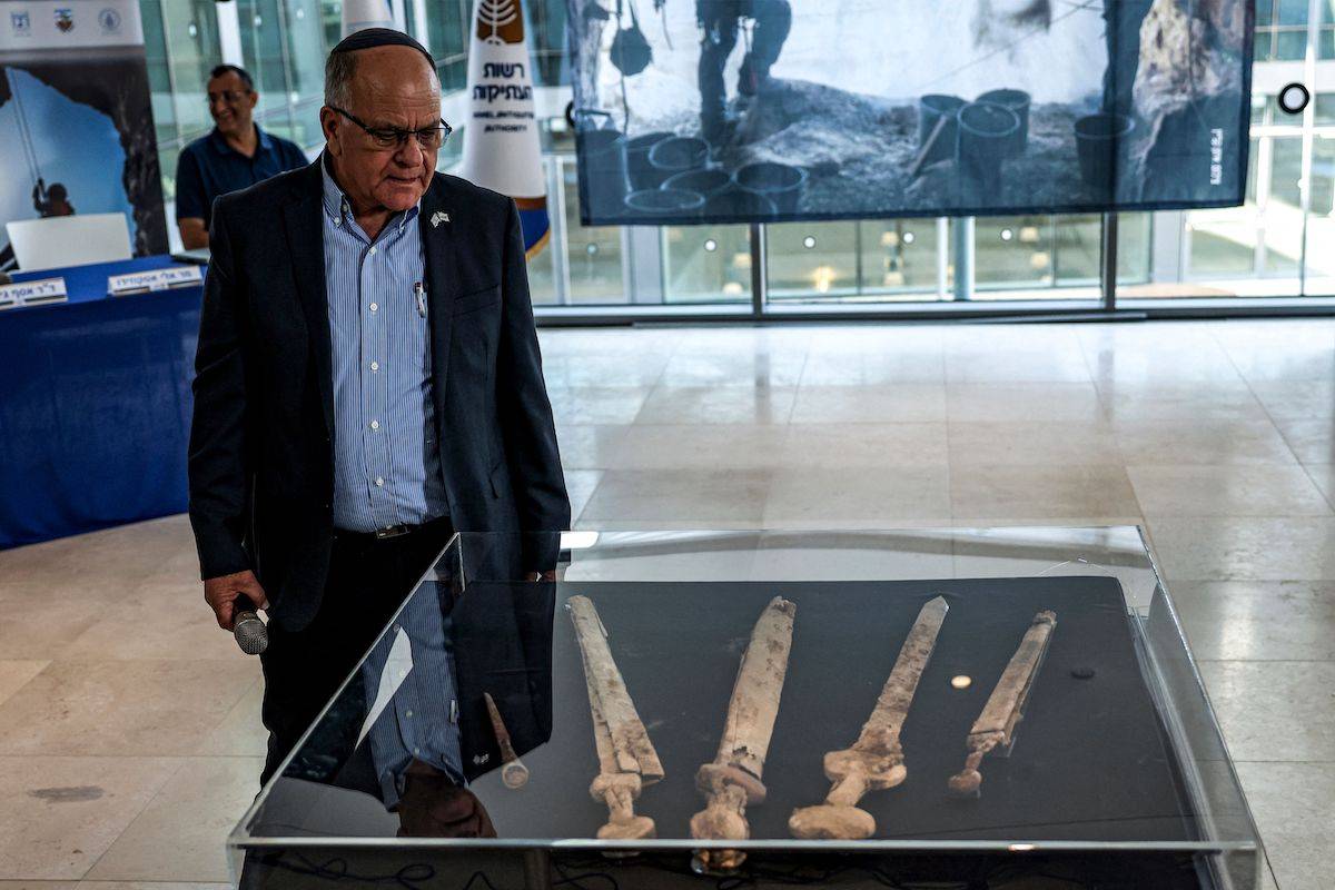 Eli Escusido, Director of the Israel Antiquities Authority (IAA), stands by a showcase displaying a shafted pilum (javelin) and four swords dating about 1,900-years-old swords, preserved in their wooden and leather scabbards, found in a Judean Desert cave, during a press conference by researchers from the IAA and Ariel University at the Jay and Jeanie Schottenstein National campus for the Archeology of Israel in Jerusalem on September 6, 2023. [RONALDO SCHEMIDT/AFP via Getty Images]