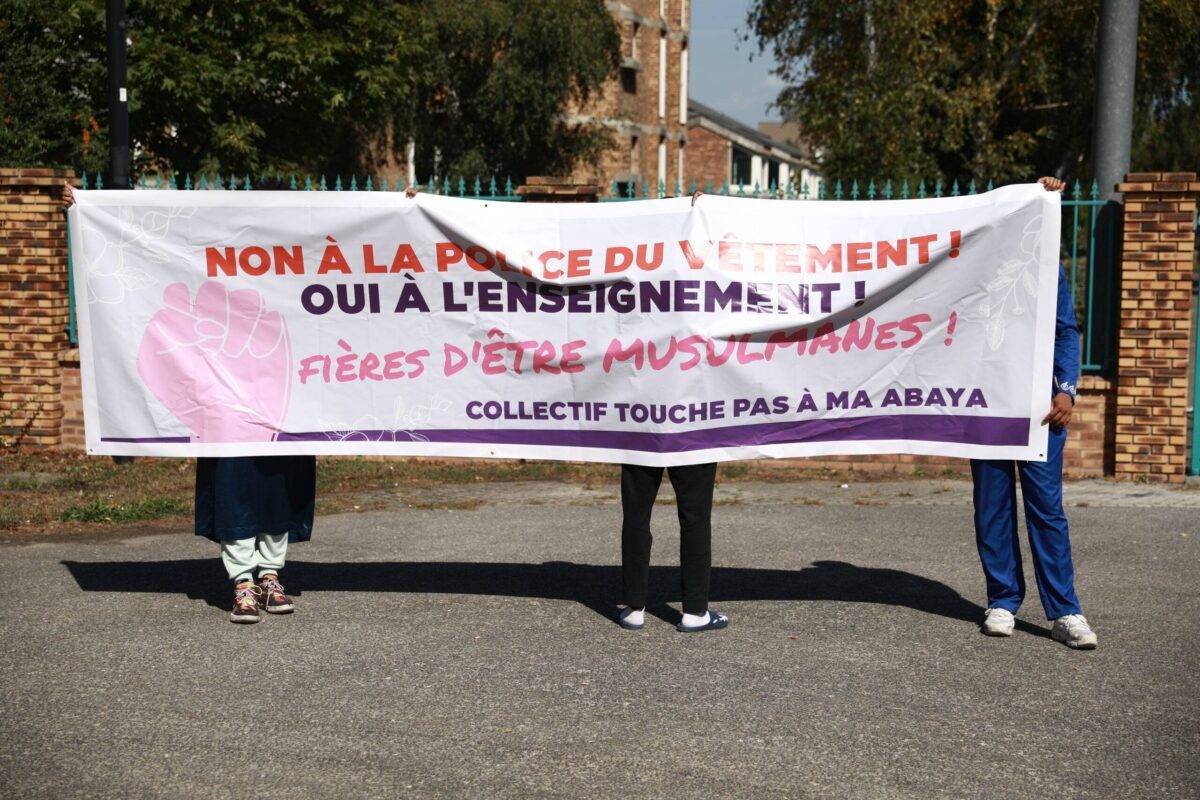 Muslim people hold a banner as they protest against the interdiction of Abaya in front of the school Lycee La Plaine de Neauphle in Trappes, France on September 08, 2023 [Mohamad Salaheldin Abdelg Alsayed/Anadolu Agency via Getty Images]