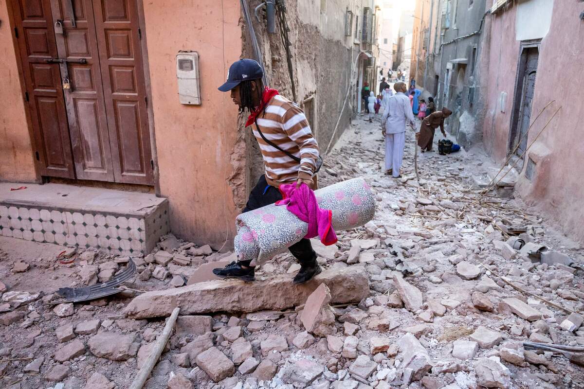 A man walks with his belongings through the rubble in an alleyway in the earthquake-damaged old city in Marrakesh on September 9, 2023. [Photo by FADEL SENNA/AFP via Getty Images]
