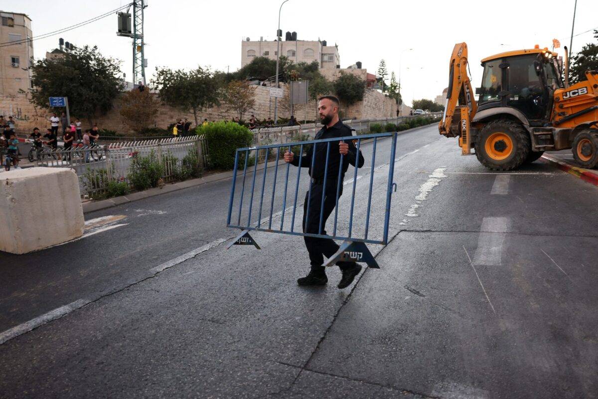 An Israeli policeman places a metallic barrier across a road linking the east Jerusalem Arab neighbourhood of Beit Hanina with west Jerusalem before the start of Yom Kippur (Day of Atonement), on September 24, 2023 [AHMAD GHARABLI/AFP via Getty Images]