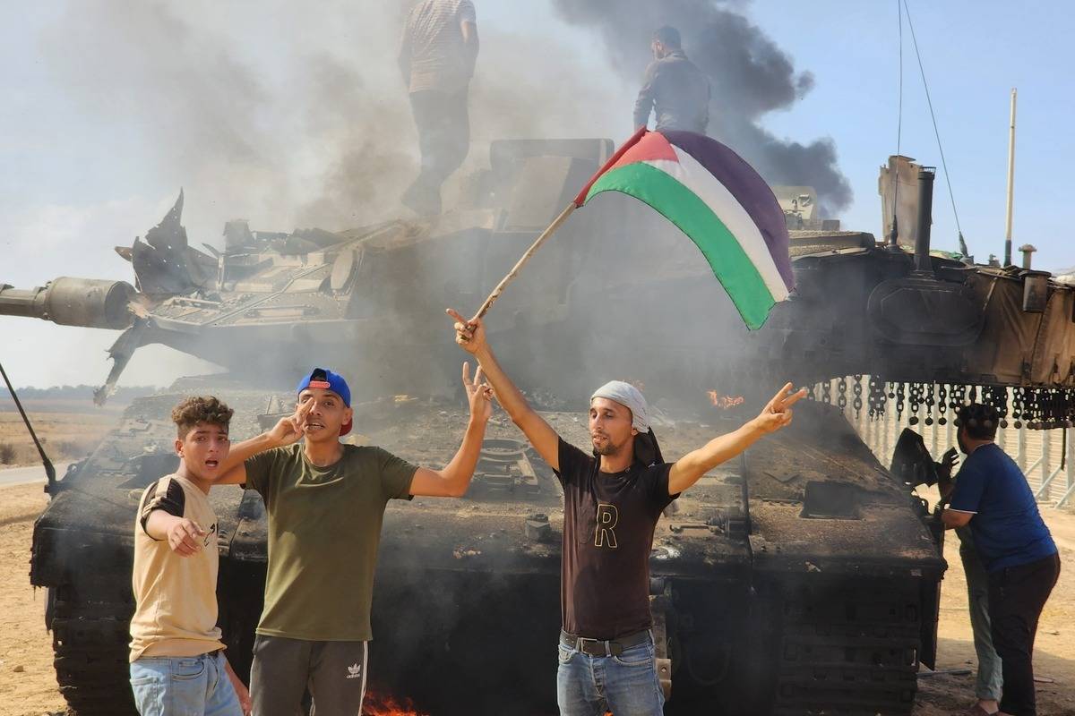 Hamas' armed wing, the Izz ad-Din al-Qassam Brigades hold a Palestinian flag as they destroy a tank of Israeli forces in Gaza City, Gaza on October 07, 2023. [Hani Alshaer - Anadolu Agency]