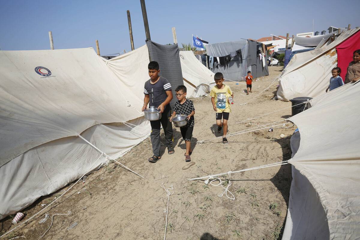 Palestinians including children are served food by United Nations Agency for Palestine Refugees (UNRWA) officials as they took refuge in UNRWA camp to flee Israeli attacks in Khan Yunis, Gaza on October 24, 2023 [Ashraf Amra/Anadolu Agency]