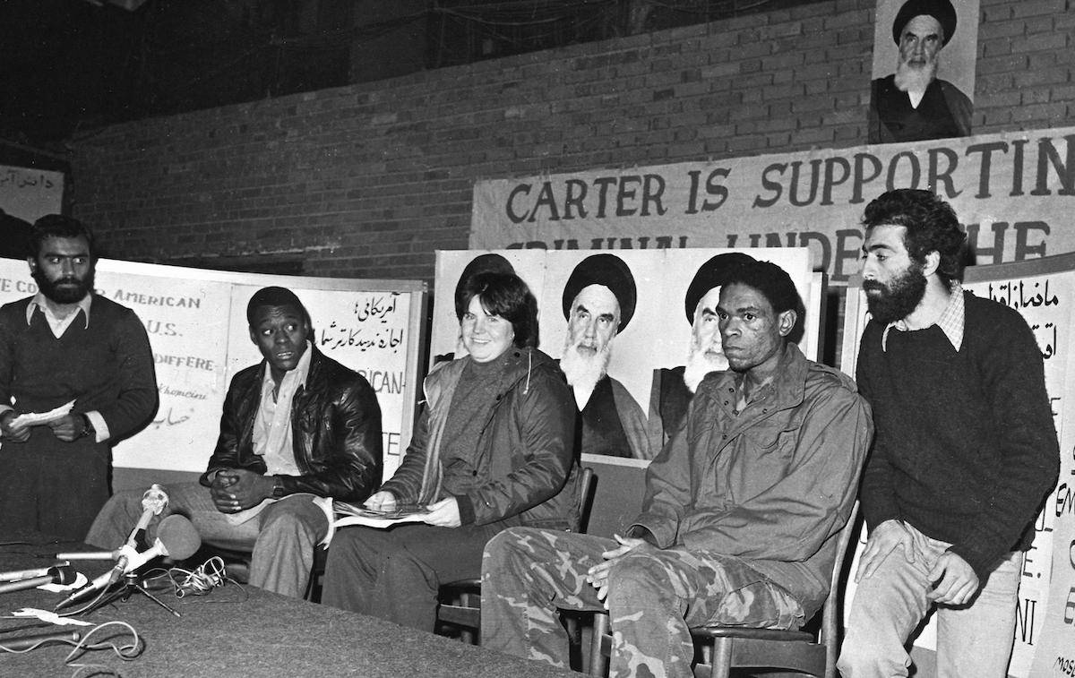 Three unidentified US hostages speak to the press while their Iranian captors (L and R) watch closely, at the besieged US embassy in Tehran, November 1979. [IRNA-FILES/AFP via Getty Images]