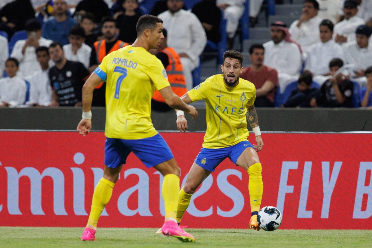 Nassr's Portuguese forward Cristiano Ronaldo (L) looks on as Nassr's Brazilian defender Alex Telles runs with the ball at the King Fahd Stadium in Taif on July 28, 2023 [AFP via Getty Images]