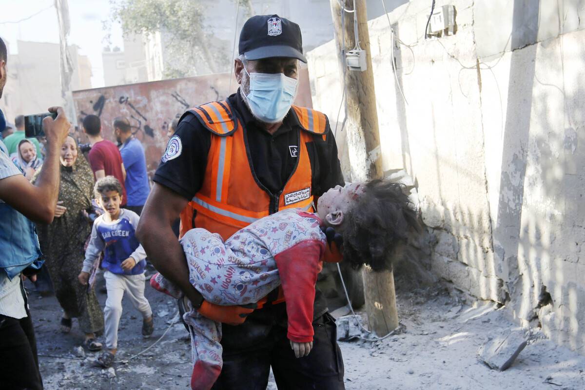 An official carries an injured child as an airstrike hits the building belonging to the Maslah family during the 32nd day of Israeli attacks in Deir Al-Balah, Gaza on November 7, 2023 [Ashraf Amra - Anadolu Agency]